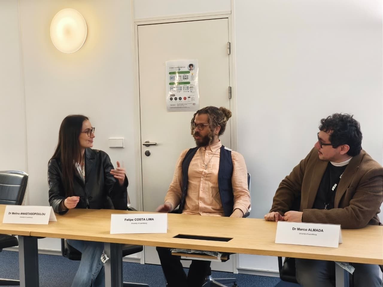 Three speakers sit at a long table. In the left-hand side of the picture, Dr Melina Anastasopoulou speaks about her work on digital sovereignty and the Laos DPR. The two other speakers, Dr Felipe Costa Lima and yours truly, listen attentively.